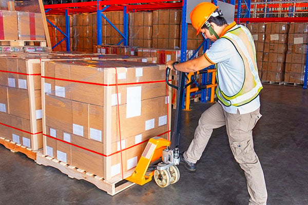 employee loads manual pallet jack in a warehouse