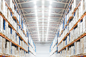 Stocked warehouse aisle with bright lights overhead.