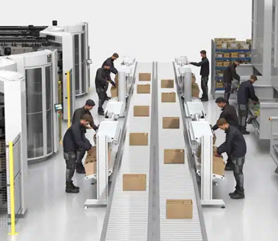 An ASRS set up in a warehouse; workers place picked boxes on conveyor from VLMs and horizontal carousels