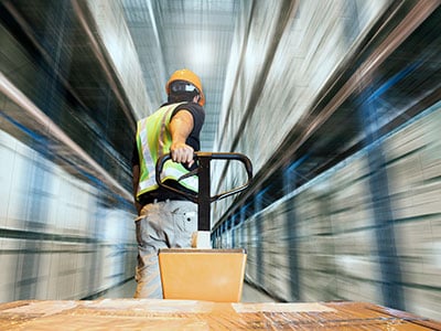 employee pulls a pallet jack at capacity down an aisle